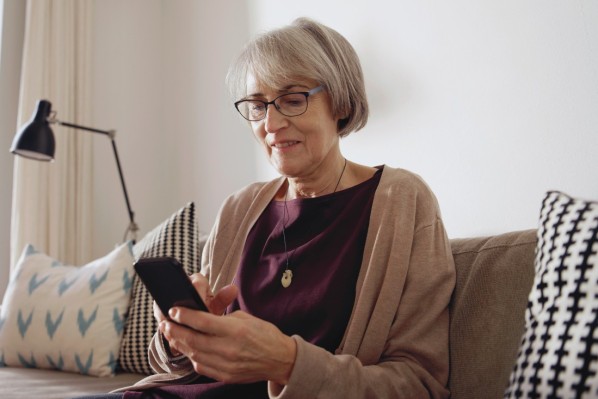 Eine ältere Frau liest ihre Emails auf einem Smartphone