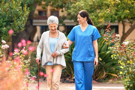 Pflegerin geht mit Seniorin spazieren