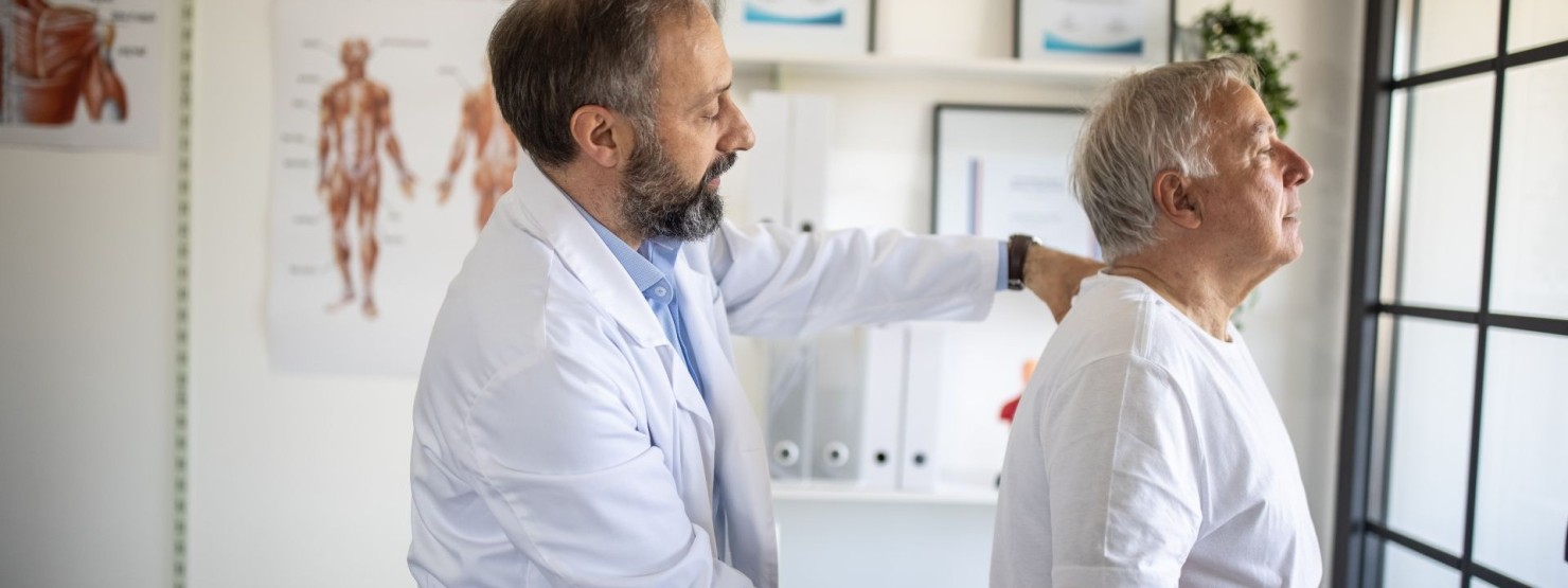 Im Rückenzentrum in Magdeburg untersucht ein Orthopäde einen Patienten am Rücken.
