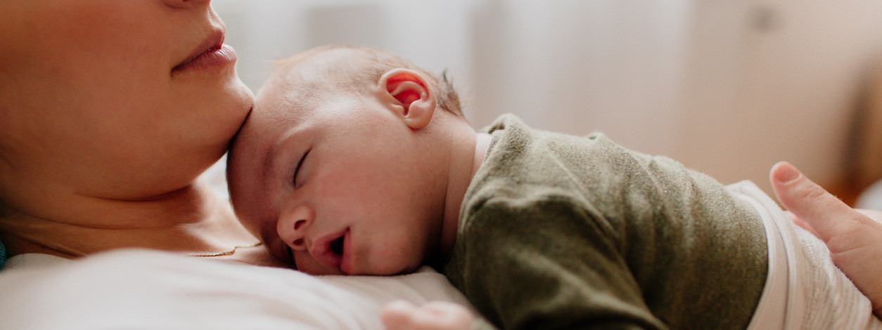 baby schläft ruhig auf dem Oberkörper der Mutter.