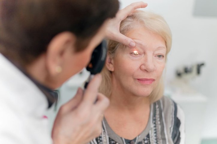 Ein Arzt untersucht das Auge einer älteren Patientin auf Grauen Star