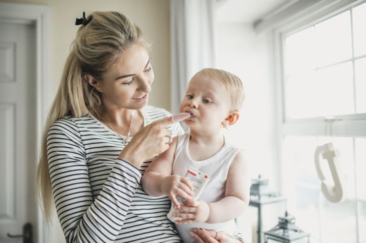 Eine Mutter wendet Zahnungsgel bei ihrem Kleinkind an