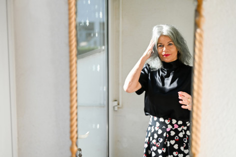 Eine Frau mit Brustprothese schaut sich im Spiegel an.