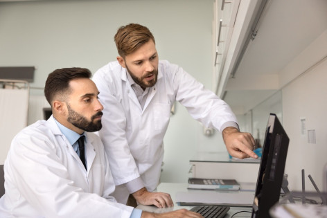 Zwei Ärzte schauen sich gemeinsam auf einem Computer die Befunde eines Patienten an.