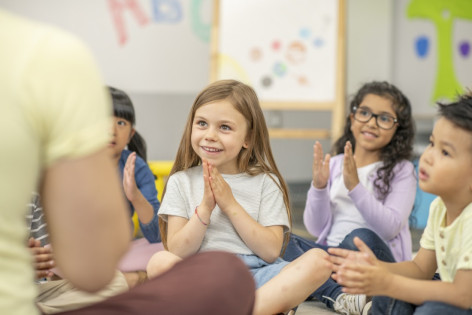 Grundschulkinder sitzen im Klassenzimemr auf dem Boden und schauen sich begeistert ein Theaterstück an.