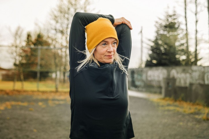eine Frau Mitte 50 macht Dehnübungen vor ihrer Jogging-Runde