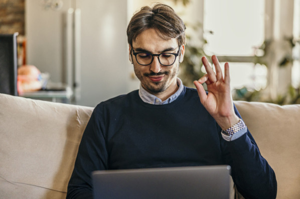 Mann am Laptop macht Kreis aus Daumen und Zeigefinger