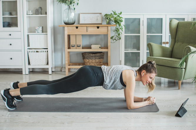 Eine Frau macht eine Unterarmstützübung auf ihrer Matte zuhause.