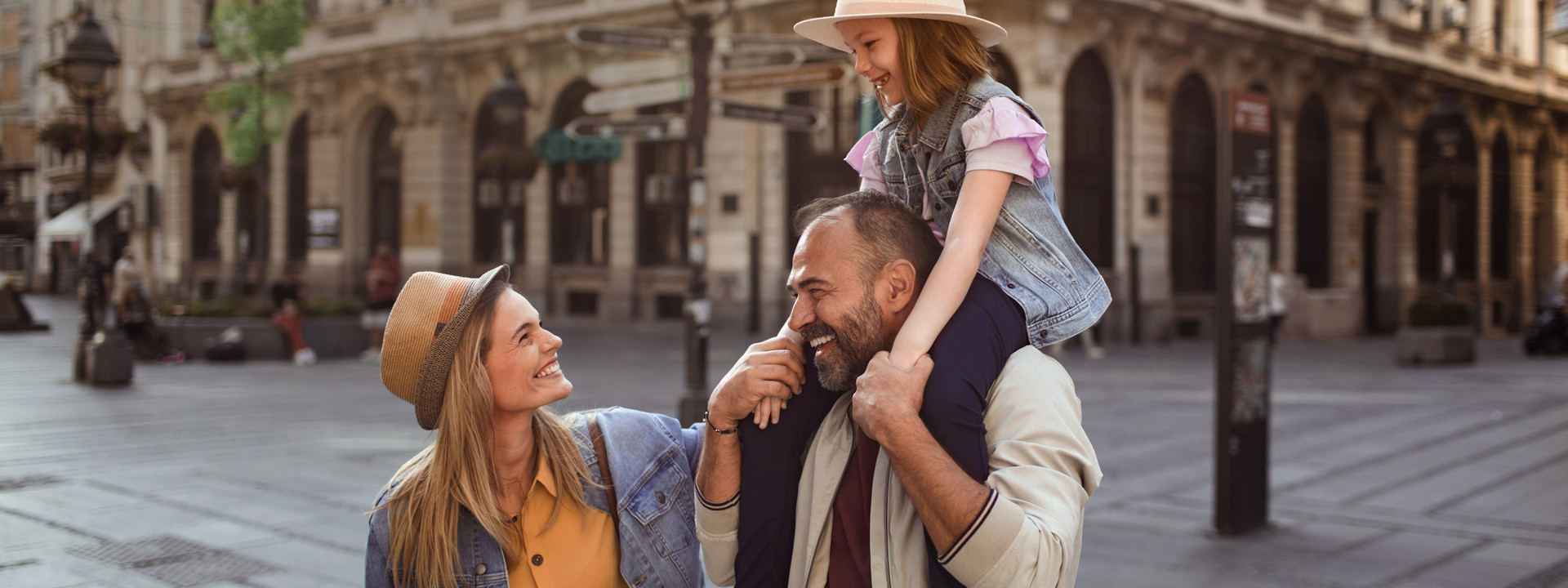 Glückliche Familie genießt Stadtbummel im Sonnenschein. - AOK Sachsen-Anhalt begleitet mit exklusiven Leistungen für Familien.
