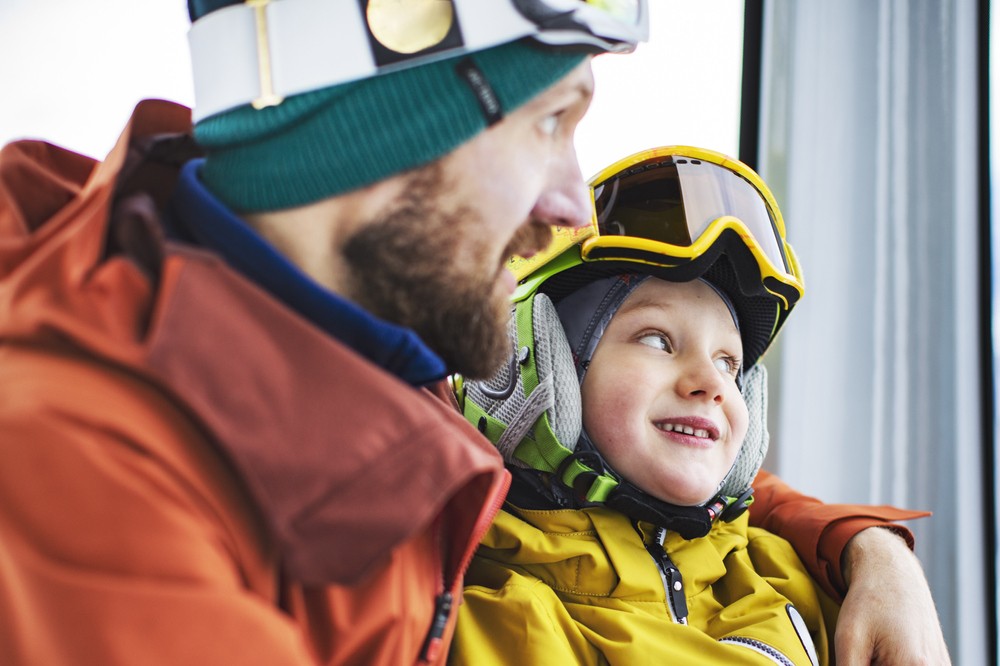 Ein vater mit seinem Kleinen Sohn in der Gondelbahn auf dem Weg zum Skifahren