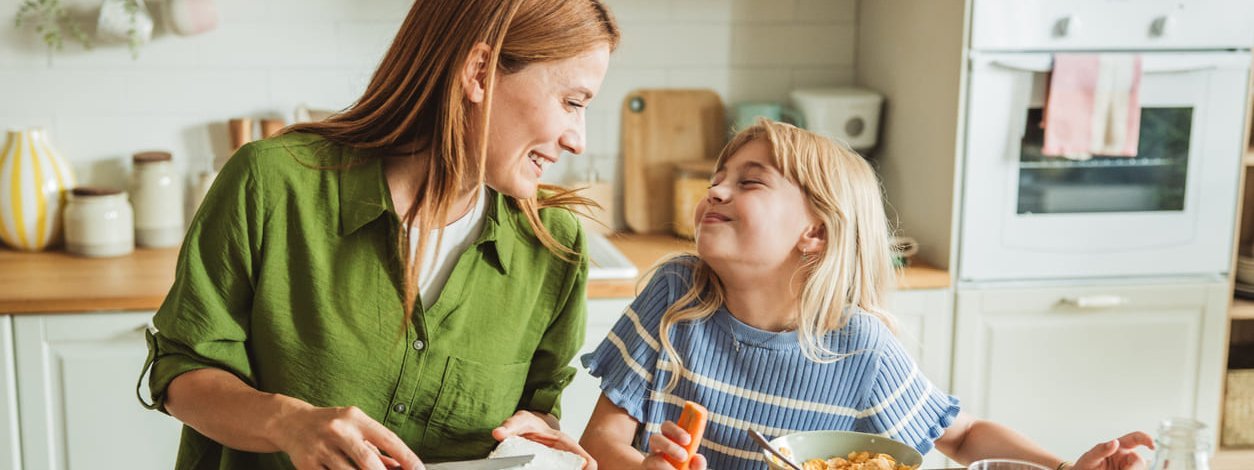 Eine Mutter bereitet mit ihrer kleinen Tochter gesunde Speisen zu.