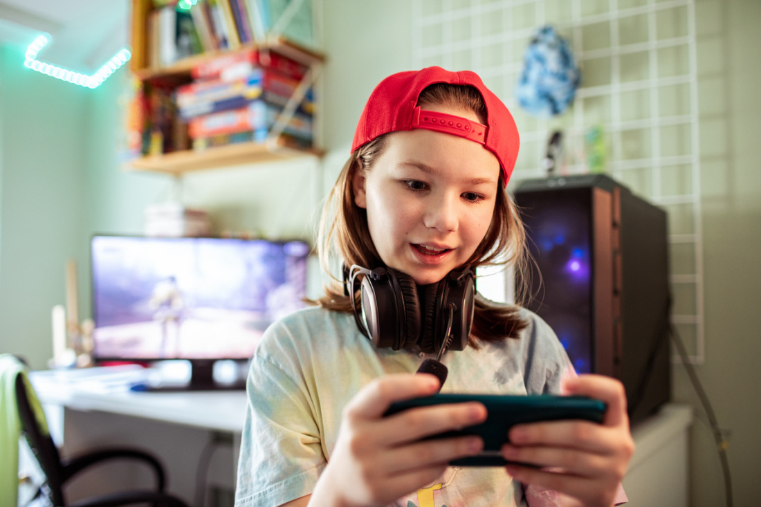 Ein junges Mädchen spielt auf ihrem Smartphone Onlinespiele.