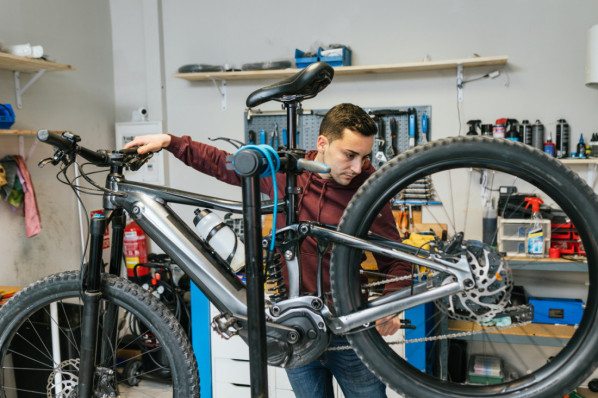 Fahrradmechaniker prüft die hintere Schaltung und die Bremsen eines Mountainbikes