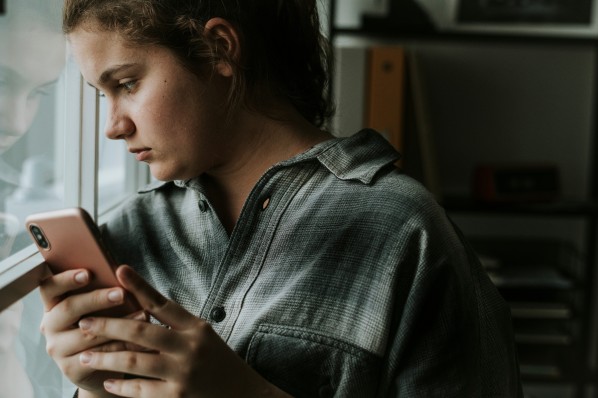 Mädchen schaut besorgt und traurig auf ihr Smartphone