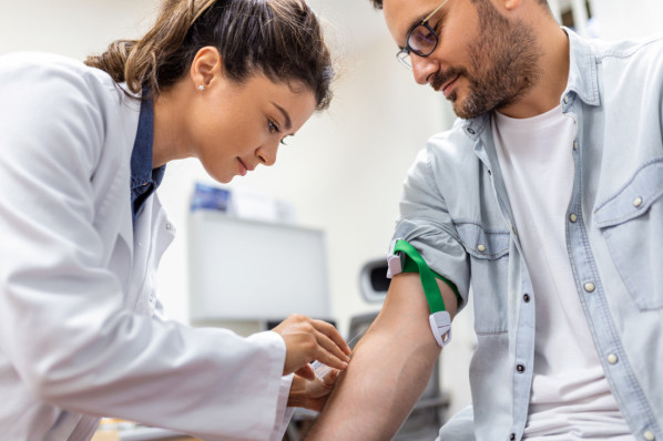 Junge Ärztin nimmt männlichem patienten Blut ab