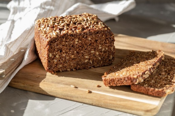 Ein Vollkornbrot und zwei Brotscheiben auf einem Holzbrett.