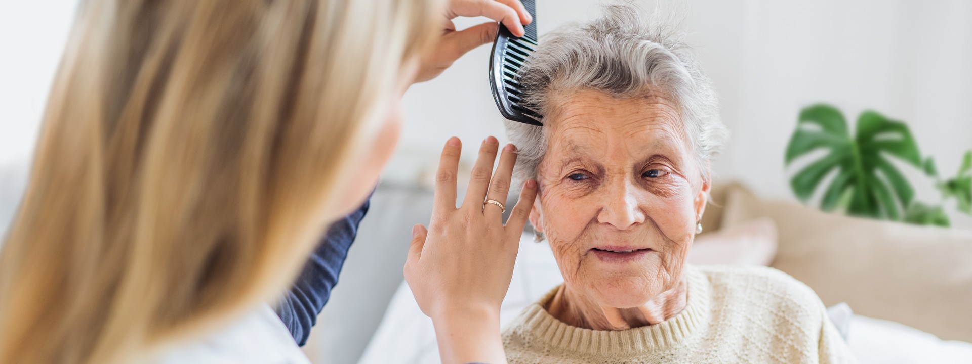 Pflegerin kämmt Seniorin die Haare