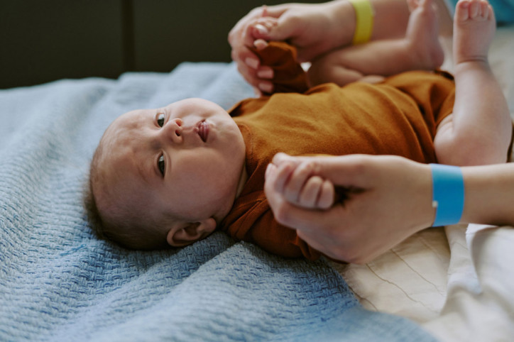 Ein Baby mit Dreimonatskoliken zieht die Beine an