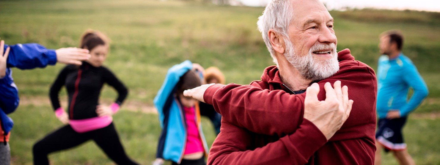 Älterer mann Mitte 60 macht dehnübungen vor einem Workout im Freien