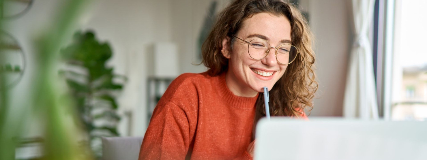 Eine Beschäftigte arbeitet lächelnd im Home Office und nimmt an der Mental Health Week teil.