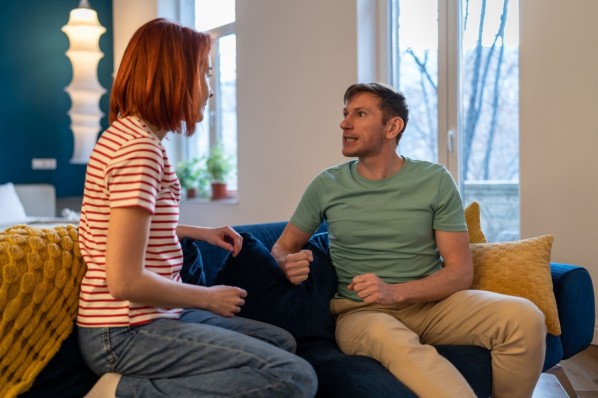 Gestresstes -Paar streitet sich emotional, während es zu Hause auf dem Sofa sitzt.