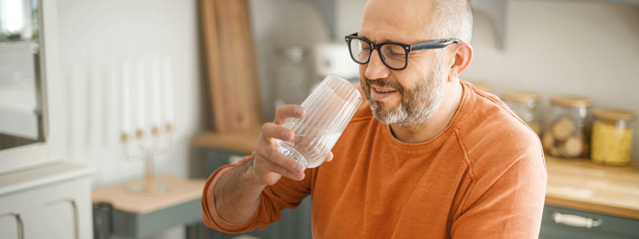 Paar mittleren Alters mit Wanderrucksäcken blicken auf einen Bergsee
