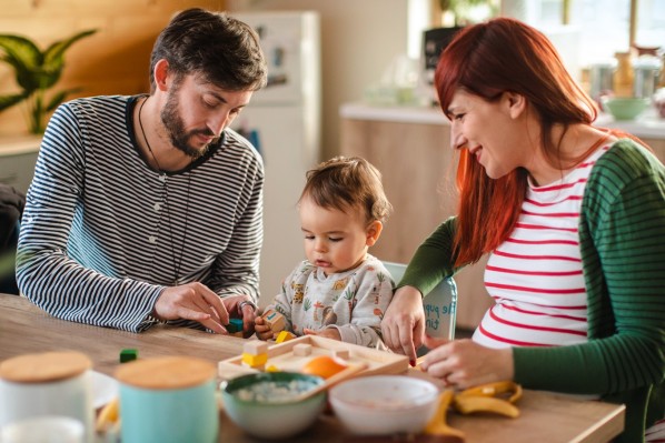 Eine etwa 30-jährige Schwangere frühstückt zusammen mit ihrem Mann und ihrem etwa 1-jährigen Kind.