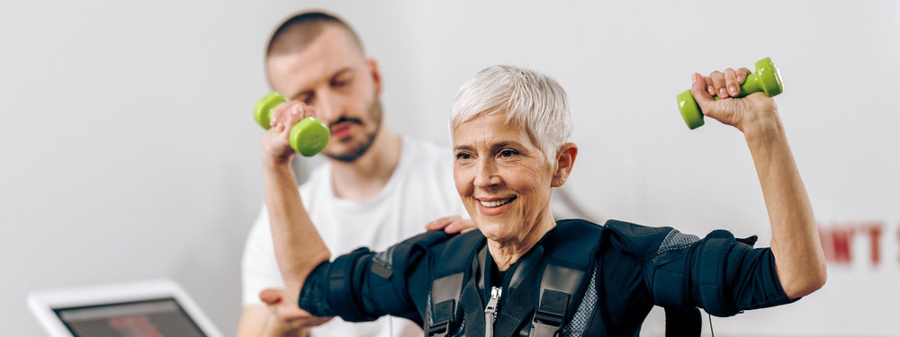 Eine ältere Frau probiert EMS-Training aus