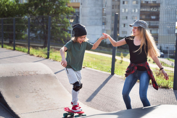 Eine Mutter übt mit ihrem Sohn Skaten im Skatepark