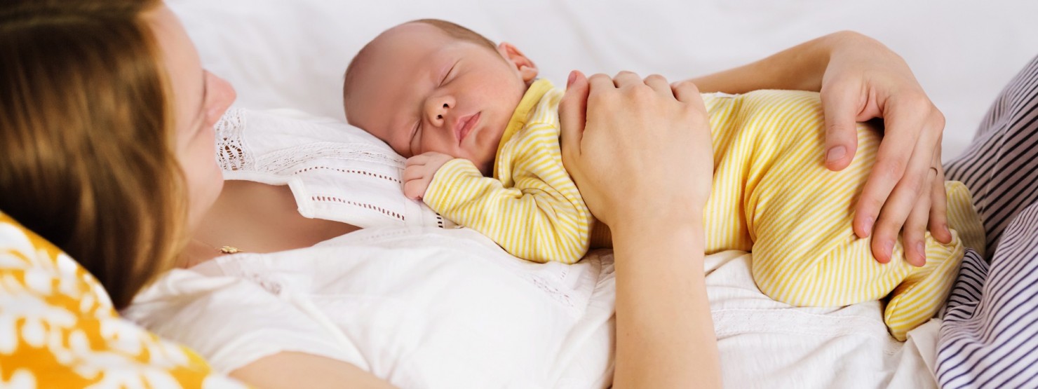 Frau mit ihrem Baby gemütlich im Bett.