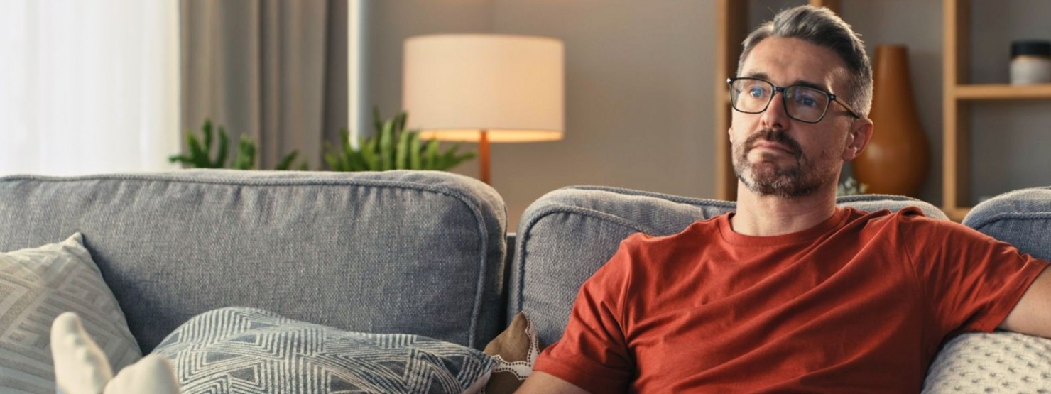 Ein etwa 40 jähriger Mann liegt auf der Couch.