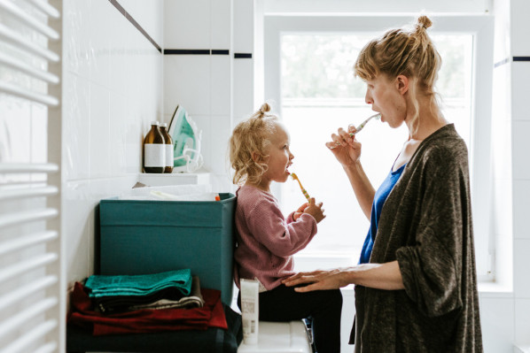 Eine Mutter putzt sich gemeinsam mit der Tochter die Zähne.