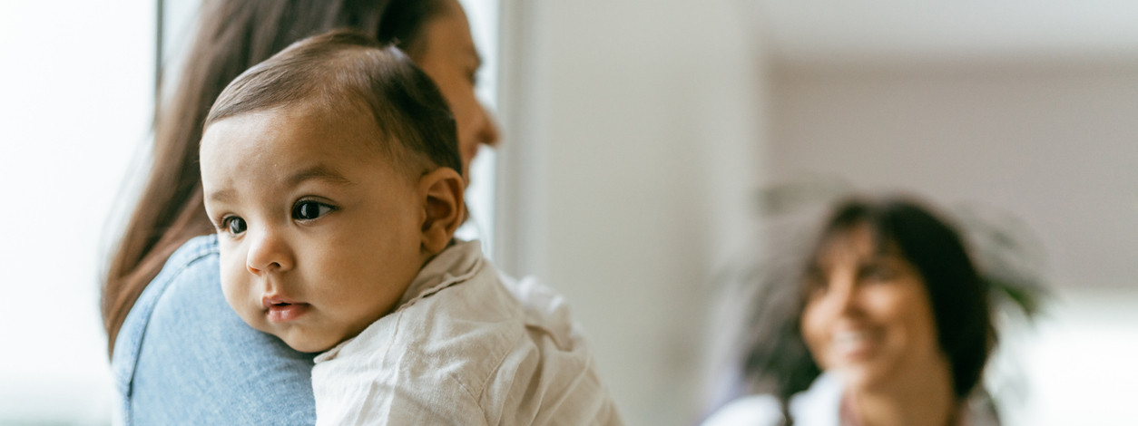 Mutter mit zirka 3 Monate altem baby auf dem Arm vor Arztbesuch