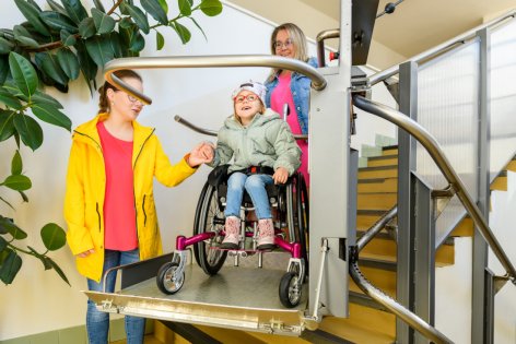 Ein Kind im Rollstuhl nutzt einen Treppenlift.
