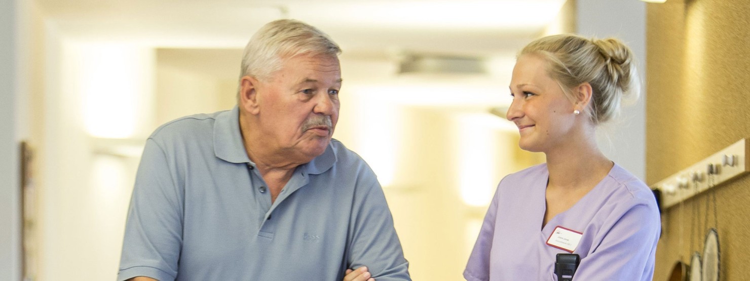Eine Pflegerin stützt einen Patienten