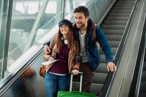 Frau und Mann lächeln auf einer Rolltreppe. 