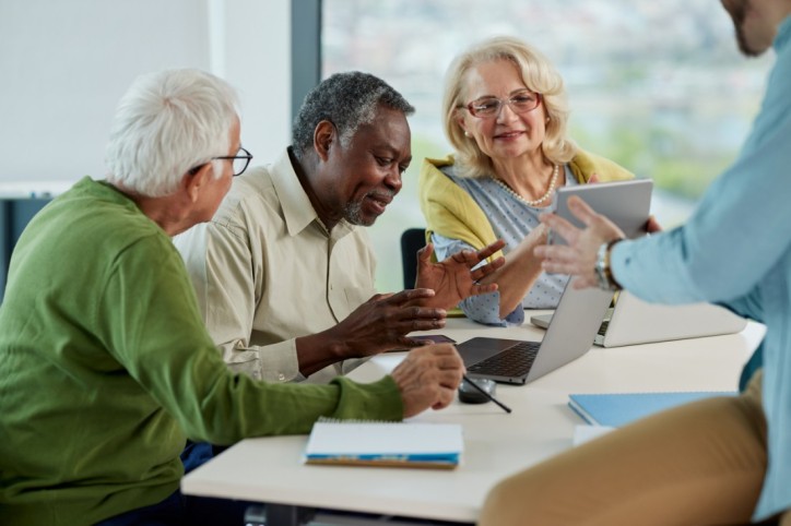 Drei Senioren lernen in einem Kurs den Umgang mit Laptop und Internet.