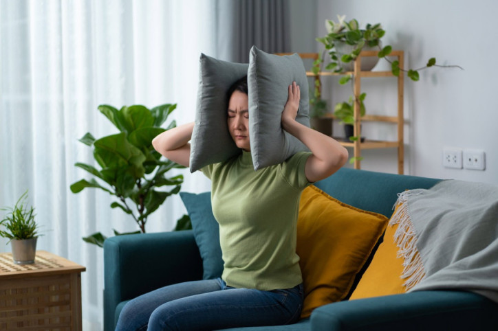 Eine Frau drückt sich wegen eines Hörsturzes Kissen auf die Ohren