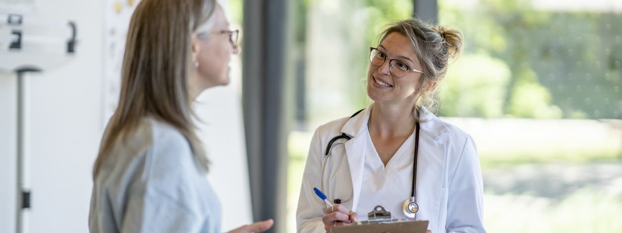 Ein Orthopäde berät eine Patientin in einer Rehaklinik.