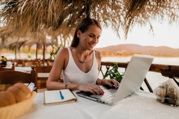Young woman studying and using a laptop in a restaurant during a vacation at the seaside