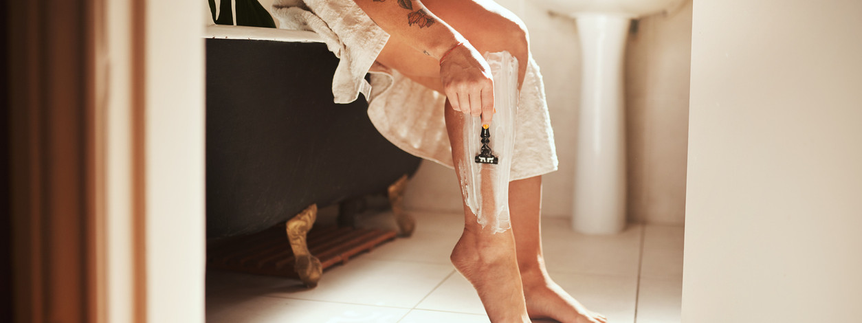 Frau rasiert ihre Beine mit einem Nassrasierer