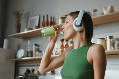 Eine Junge Frau trinkt einen Smoothie, um einem Vitaminmangel vorzubeugen