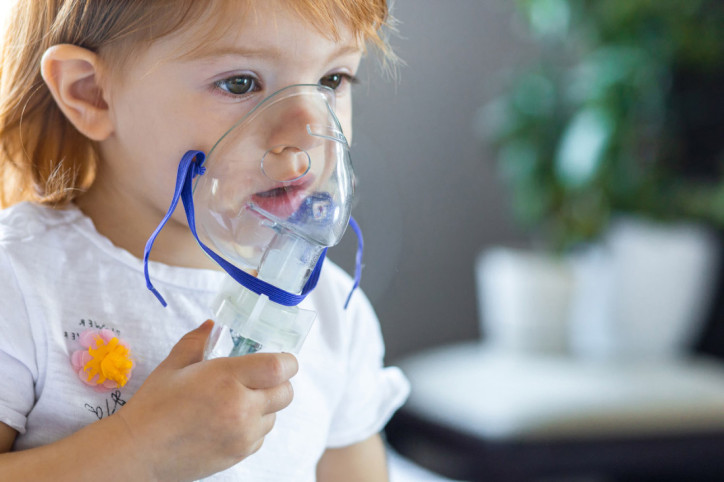 Ein kleines Mädchen mit Mukoviszidose atmet Sauerstoff