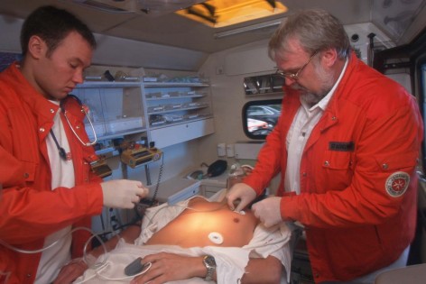 2 Sanitäter versorgen einen männlichen Patienten im Krankenwagen