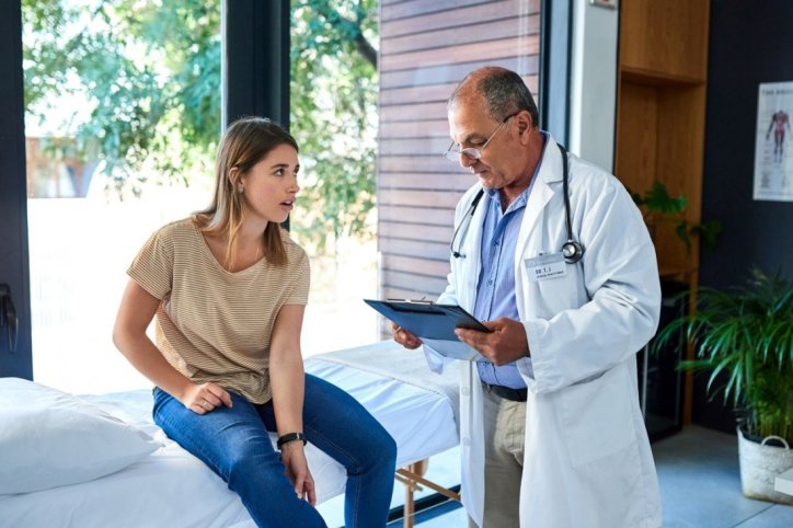 Eine junge Frau lässt sich von ihrem Arzt zu Osteoporose beraten