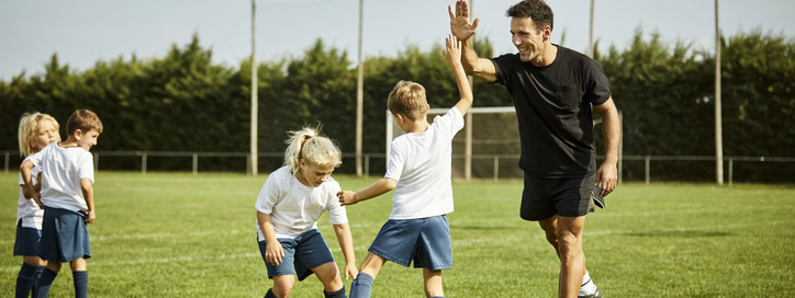 Eine Kinderfußballmannschaft freut sich gemeinsam mit ihrem Trainer.
