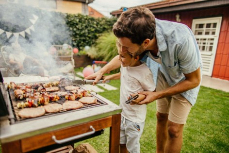 Ein Vater grillt gemeinsam mit seinem kleinen Sohn