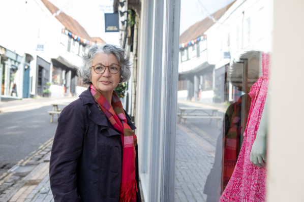Eine Frau bliebt vor einem Schaufenster stehen, um Schmerzen bei Gehen zu vertuschen