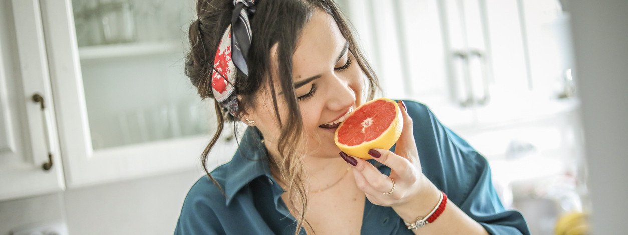 Eine Frau beißt in eine Grapefruit, die viele Bitterstoffe enthält