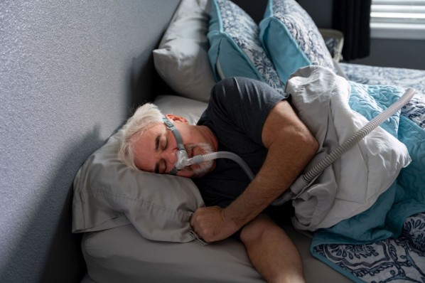 Ein älter Mann wird durch ein CPAP-Gerät beim Schlafen mit Sauerstoff versorgt